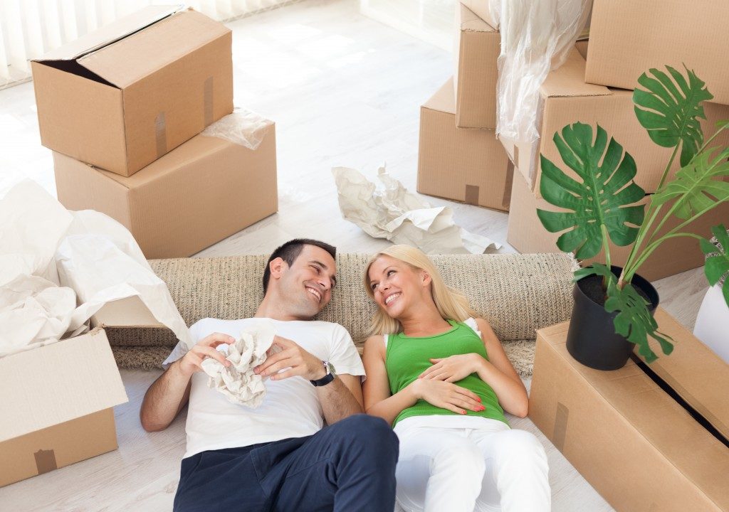Young smiling couple relaxing in the middle of cardboard boxes